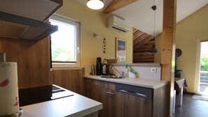 Une cuisine avec des meubles de rangement en bois, un lave-vaisselle, une machine à café et une fenêtre.