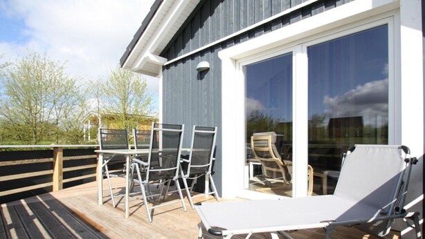 Une terrasse aménagée avec du mobilier d’extérieur, notamment une table, des chaises et un transat.