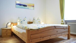 A bedroom with a wooden bed, a nightstand with a lamp, a wall-mounted painting, and a window with curtains. - Apartment in Haidmuhle With Balcony or Terrace (Haidmuhle)