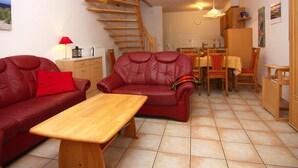 Un espacio habitable compacto con un sofá, una mesa de comedor y una escalera.