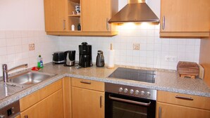 Una cocina con armarios de madera, una campana extractora de acero inoxidable, horno integrado, encimera de granito y un fregadero.