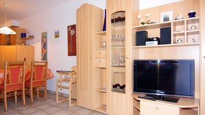Un espacio habitable pequeño con televisión, muebles de madera y una estantería.