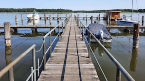 A wooden pier extending into calm water with boats docked at the end. - Ferienwohnung am Oase am Vilzsee (Mirow)
