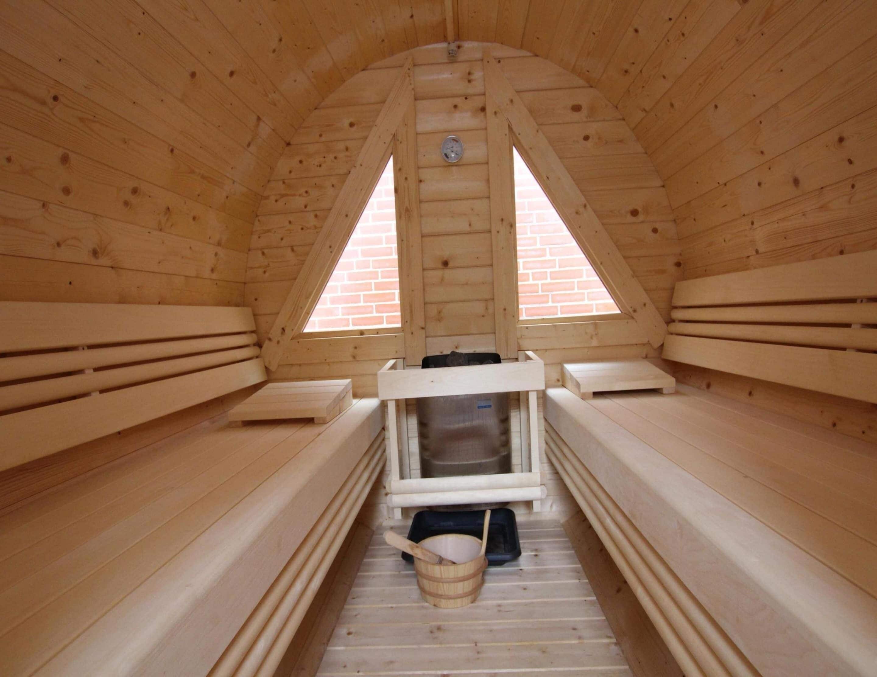 Een sauna met houten banken, een bankverwarming en een klein emmertje.