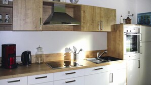 A modern kitchen with white cabinets, a stainless steel sink, and a built-in oven. - Ferienhaus Christina, Burhave (Butjadingen)
