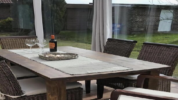 An outdoor dining area with a wooden table and wicker chairs. - Ferienhaus Christina, Burhave (Butjadingen)
