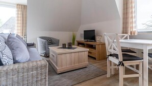 Un salon moderne comprenant un canapé, une table basse, un meuble pour la télévision et un coin repas.