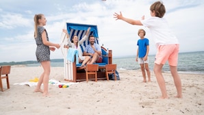 A beach scene with a lounge chair and a person sitting in it. - Appartements im Freizeitpark Weissenhauser Strand (Wangels)
