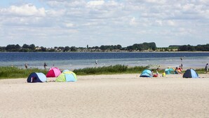 A beach with several colorful tents and a calm lake in the background. - Ferienhaus in Wohlenberg Nahe der Ostsee (Klütz)