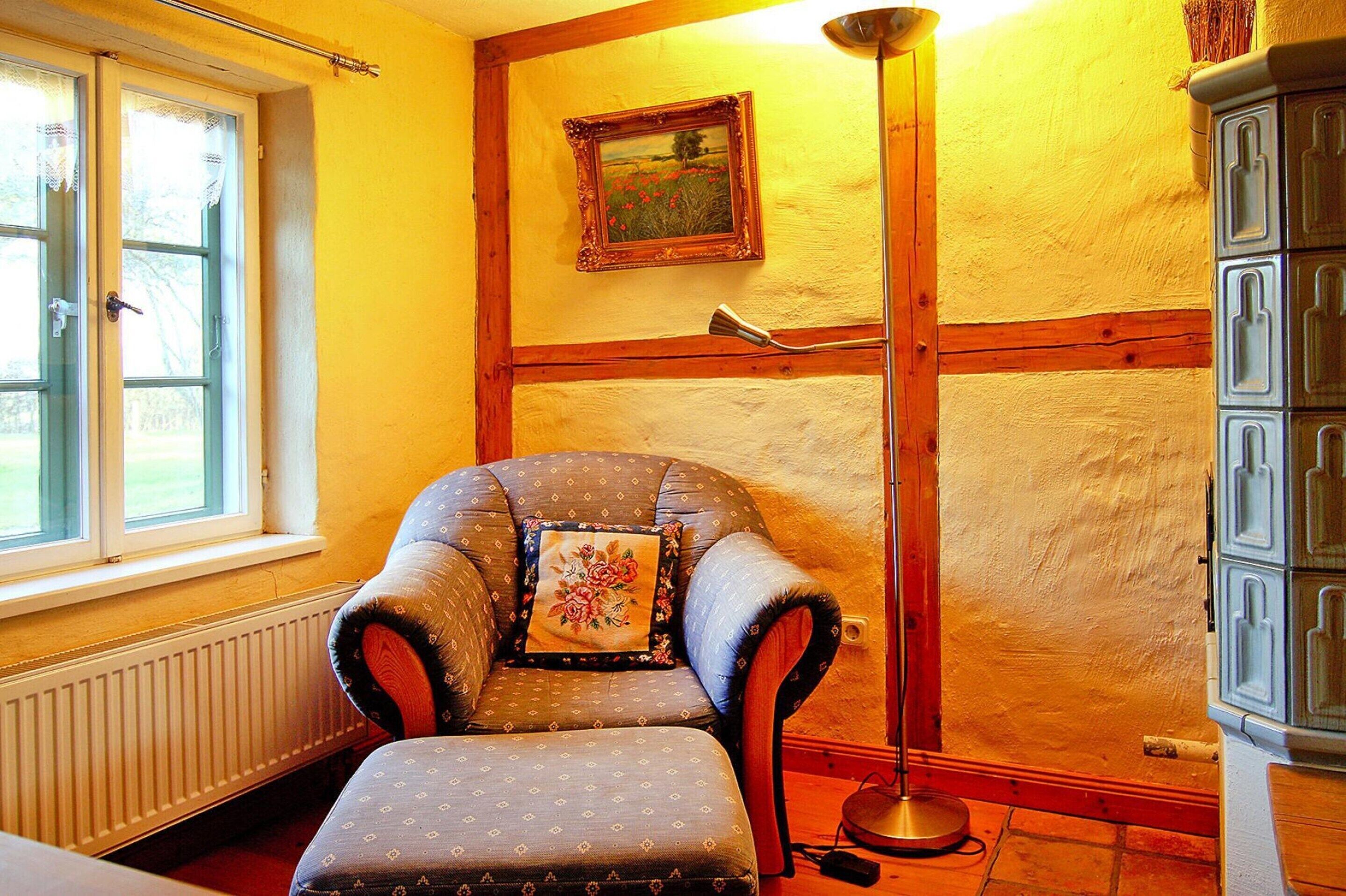 A room with a chair, a radiator, a picture on the wall, and a cabinet.
