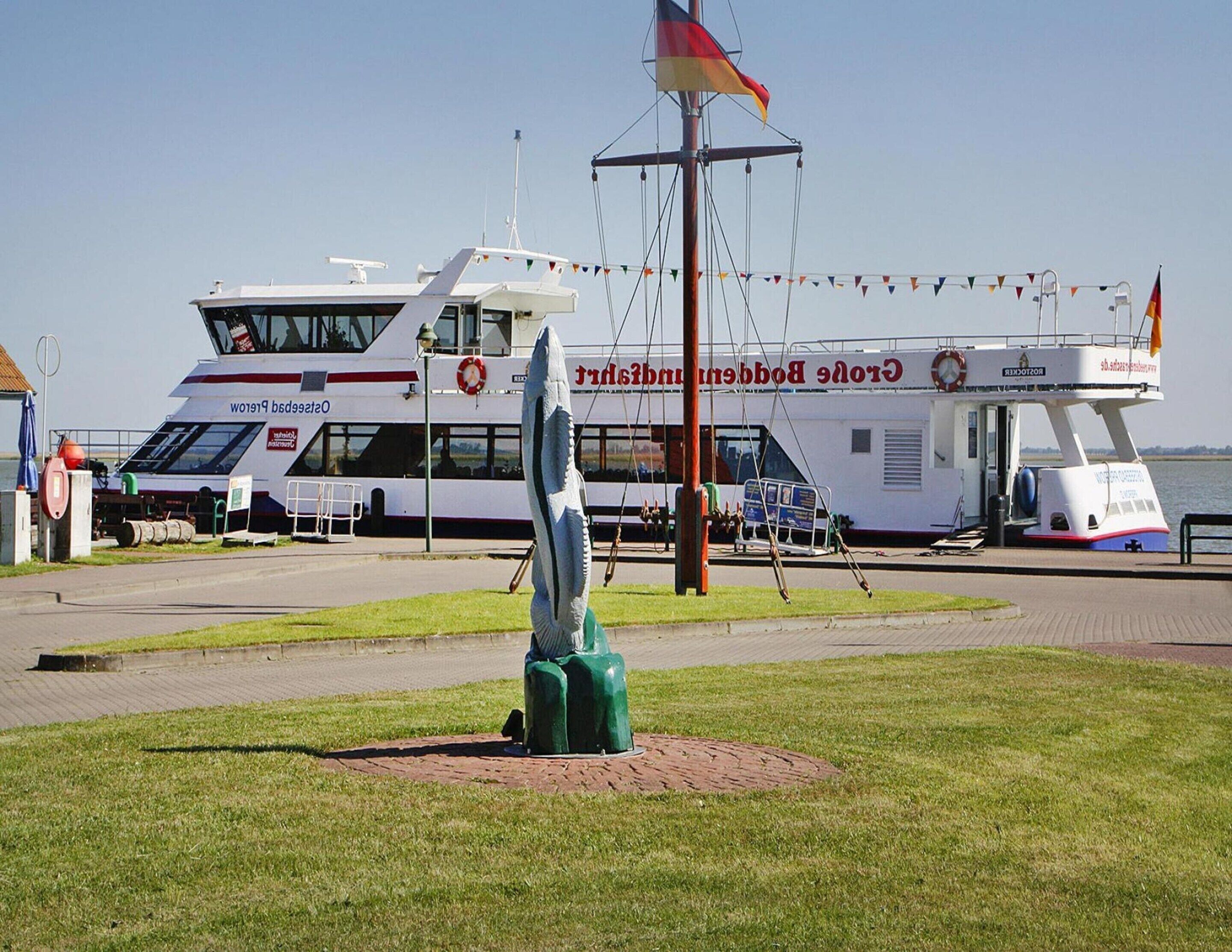 A boat docked at a marina with a lifebuoy and a flag.