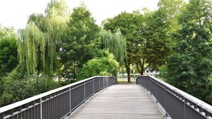 A wooden bridge with metal railings, surrounded by trees and greenery. - Appartements mit Blick auf die Spree in Lubben (Lübben (Spreewald))