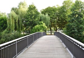 A wooden bridge with metal railings, surrounded by trees and greenery. - Appartements mit Blick auf die Spree in Lubben (Lübben (Spreewald))