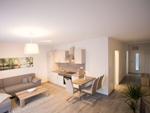 En modern lägenhet med vardagsrum, kök och matplats.
