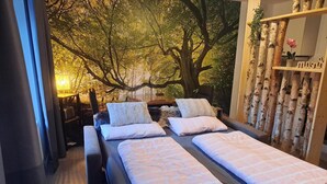 A bedroom with a large bed, two smaller beds, a wooden bench, and a wall mural of trees. - Studio in Winterberg Near Ski Slopes (Winterberg)