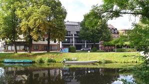 A residential area with a pond, trees, and a building with balconies. - Appartements mit Blick auf die Spree in Lubben (Lübben (Spreewald))