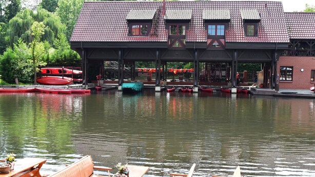 A riverside building with a covered seating area and canoes. - Appartements mit Blick auf die Spree in Lubben (Lübben (Spreewald))