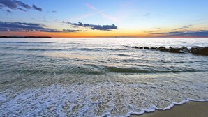 A beach with waves gently lapping at the shore, a clear sky, and a distant horizon. - Komfortable Ferienwohnung im Seepark Sellin (Sellin)