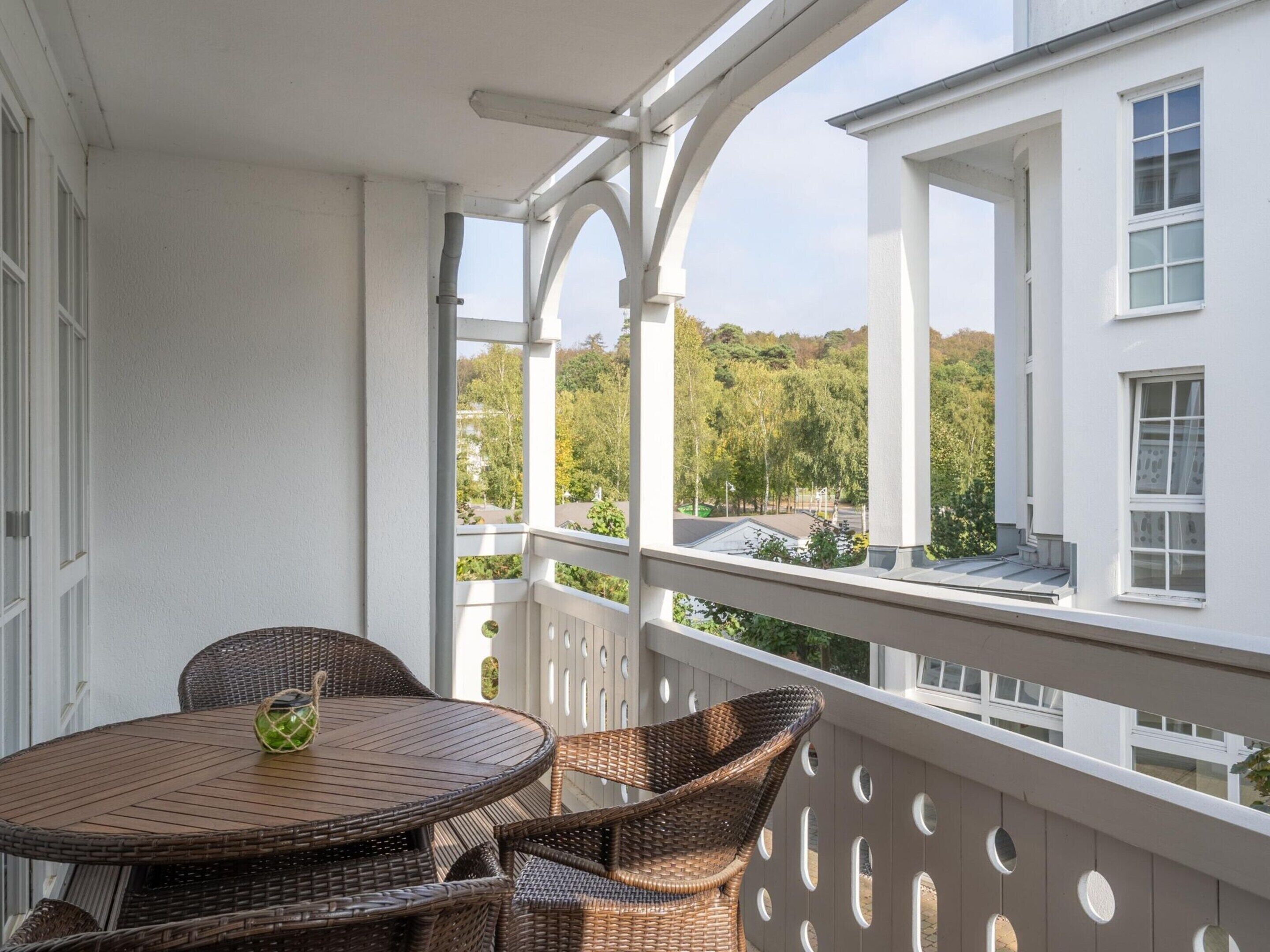 Een balkon met rieten meubilair en uitzicht op een woonwijk.