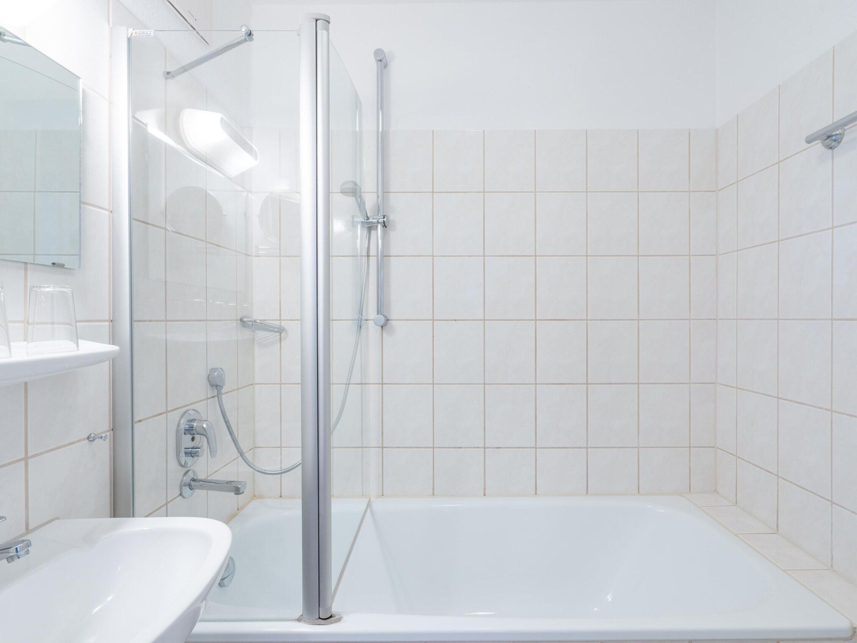 Un baño moderno con ducha envuelta en vidrio, un lavamanos blanco y una bañera.