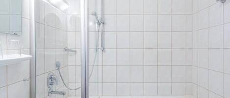 Un baño moderno con ducha envuelta en vidrio, un lavamanos blanco y una bañera.