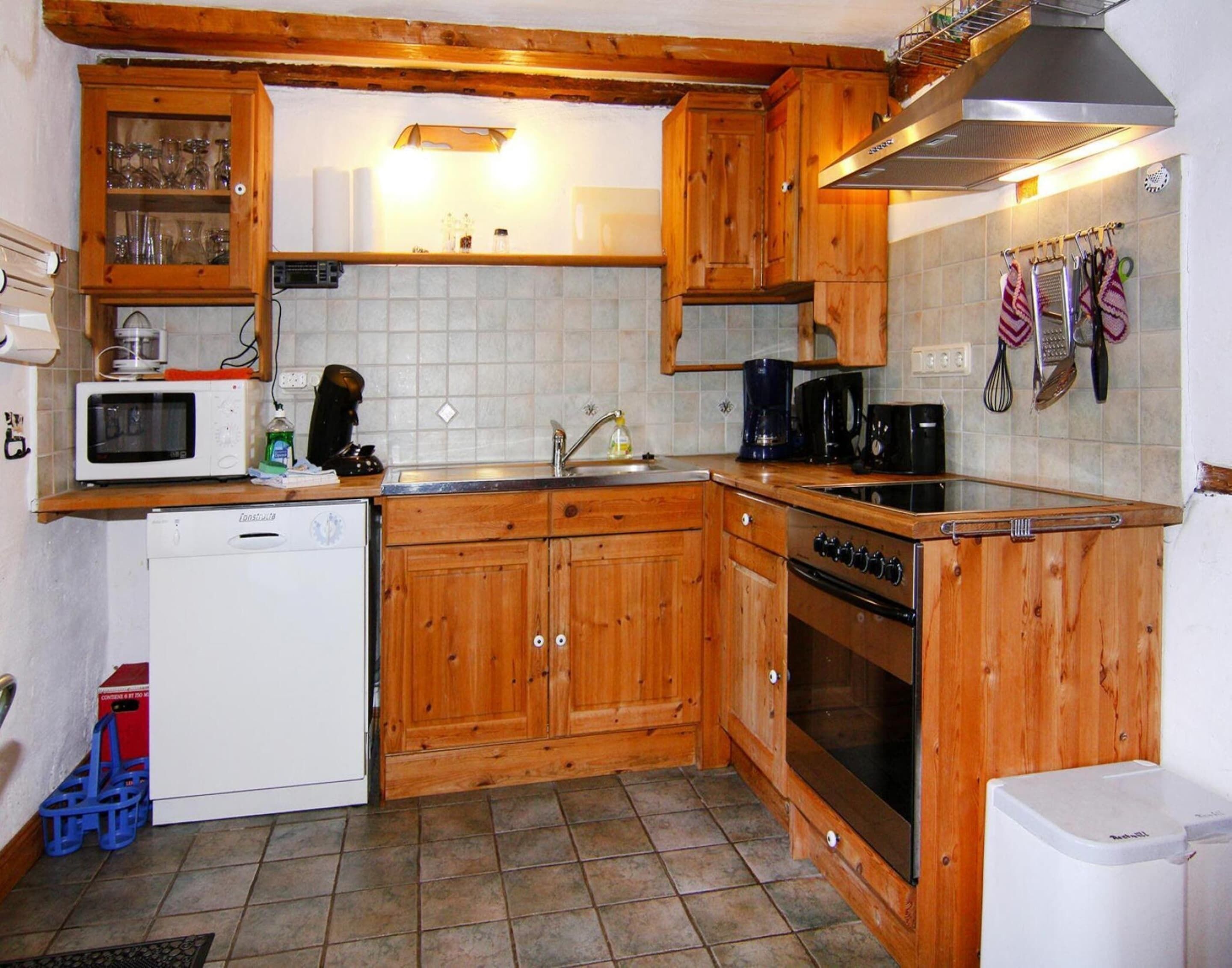 Una cocina compacta con armarios de madera, un microondas, una cafetera y un lavavajillas.