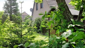 Una casa de techo inclinado, rodeada de abundante vegetación y árboles.