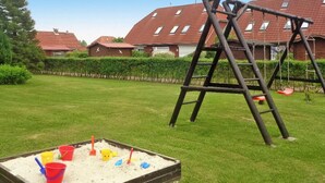 Un parque infantil con una estructura de madera para escalar y un arenero lleno de juguetes.