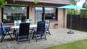 Un patio con mobiliario exterior, una casa de ladrillo y una sombrilla azul.
