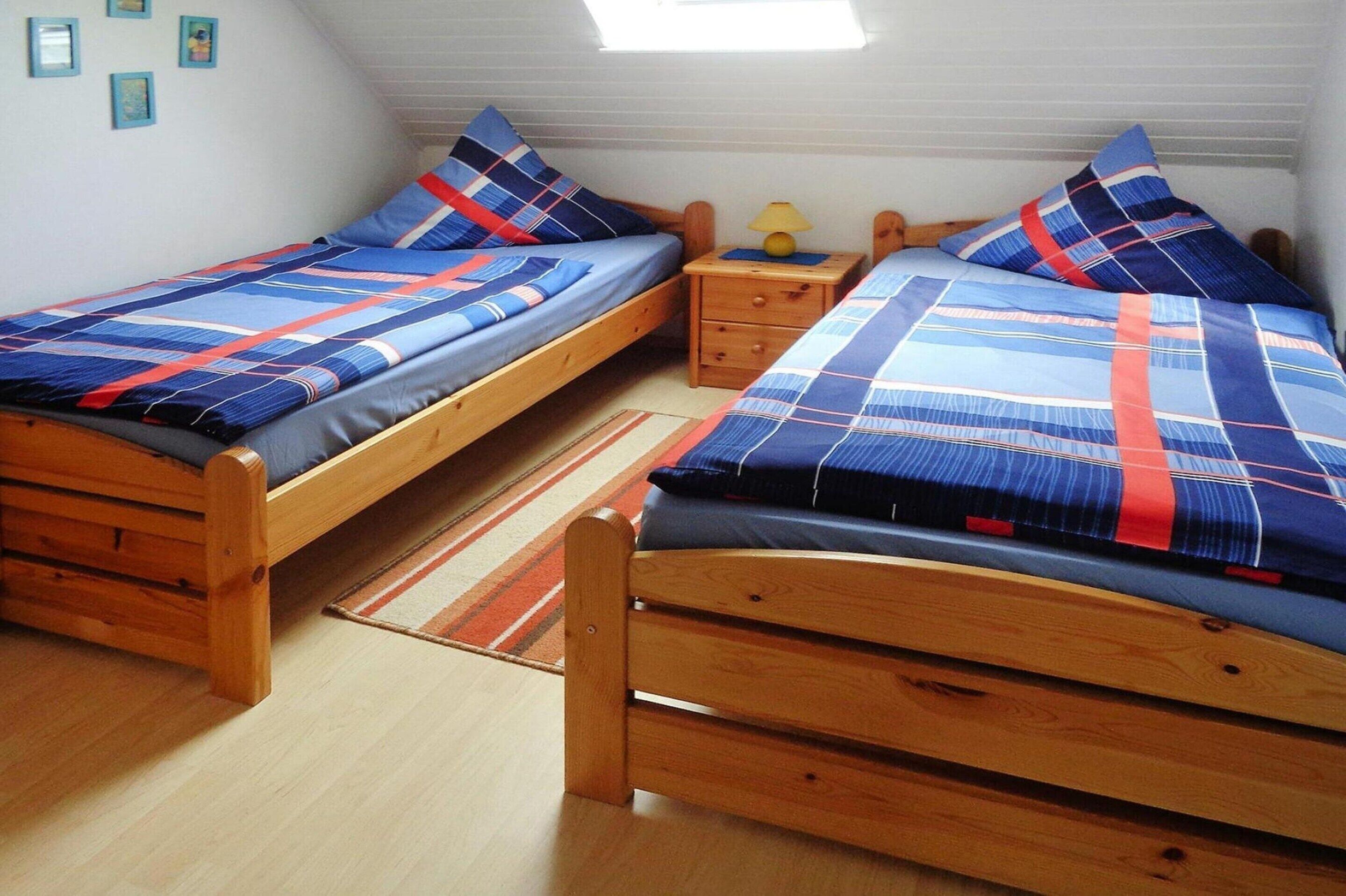 Ein Schlafzimmer mit zwei Holzbetten, einem Nachttisch und einem kleinen Tisch mit Lampe.