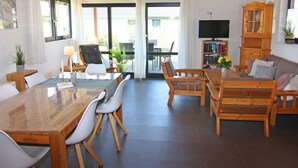 Un vaste espace de vie comprenant une table à manger en bois, des chaises, un canapé et un téléviseur.