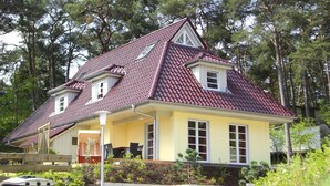 A two-story house with a red-tiled roof, a balcony, and a porch. - Doppelhaushalfte Ostseehaus II, Trassenheide (Trassenheide)