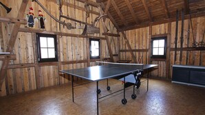 A ping pong table in a wooden room with windows and rustic decor.