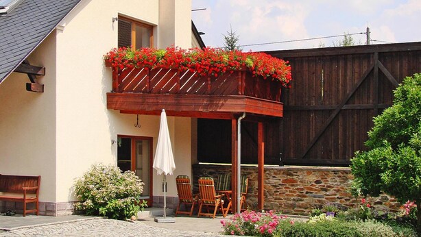 A house with a balcony, a wooden fence, and a garden.