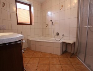 A bathroom with a bathtub, a shower, and a window.