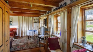 Ein gemütliches Blockhaus-Interieur mit Holzdielen, einer Couch, einem Tisch und einem Fenster mit Vorhängen.