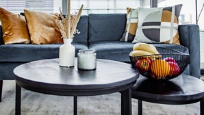 Una sala de estar moderna con un sofá gris, una mesa de centro redonda y un cuenco de fruta.