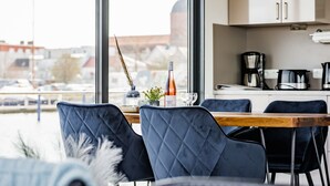 Una cocina moderna con un amplio ventanal, una mesa de comedor y sillas azules.