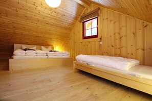 A wooden cabin room with two beds, a window, and a sloped ceiling. - Ferienhaus in Schierke mit Garten (Wernigerode)