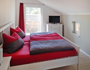Una camera da letto con un letto, una TV, una finestra e un tavolino.
