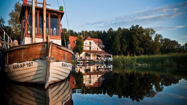 A wooden boat named BAR-AP 107 docked near a house with a reflection in the water. - Ferienhaus Bel Ami, Nakenstorf (Zurow)