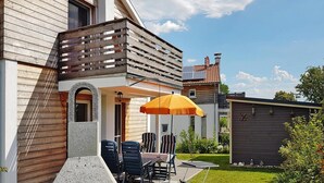 A modern house with a patio area featuring a grill, outdoor furniture, and a small garden. - Ferienhaus Bel Ami, Nakenstorf (Zurow)