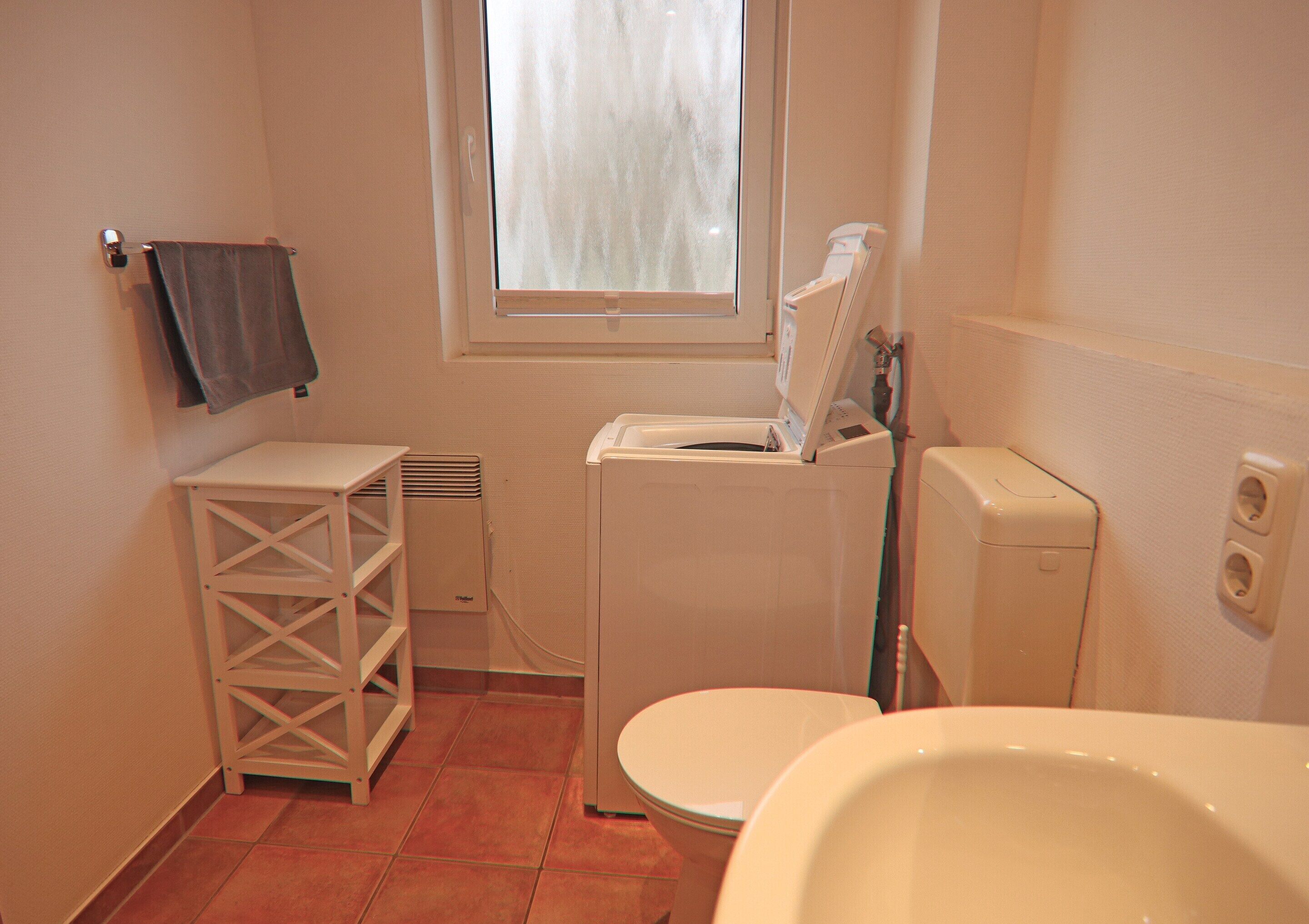 A small bathroom with a toilet, a washing machine, and a sink.