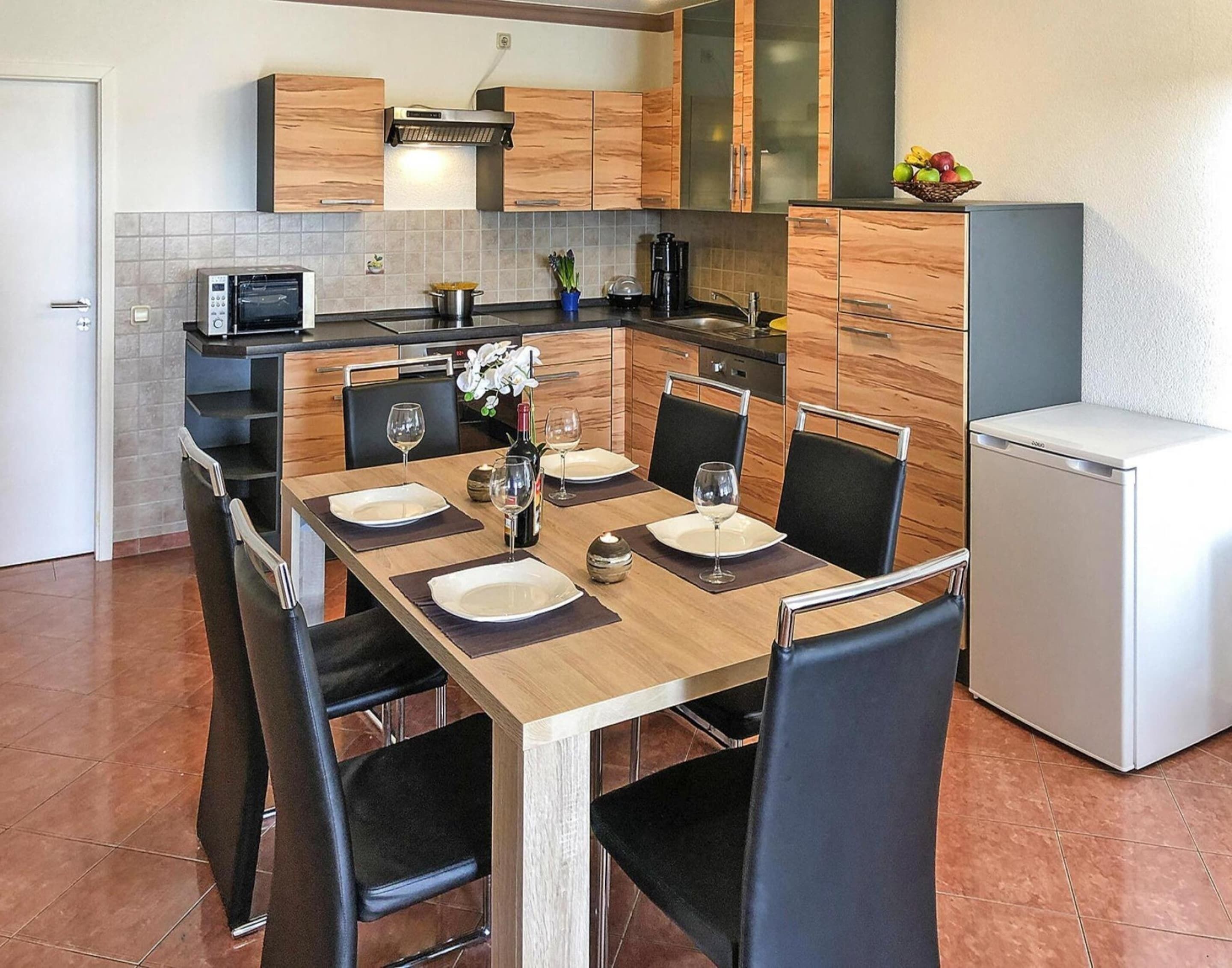 Une cuisine compacte avec une table à manger pour quatre personnes, équipée d’un four à micro-ondes, d’un four traditionnel et d’un petit réfrigérateur.