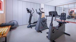 A gym with cardio machines, a bench, and a mirrored wall. - Apartments, Gohren (Göhren)