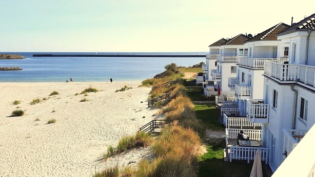 Un hôtel situé en bord de mer, doté de nombreux balcons, d’une plage de sable et offrant une vue dégagée sur la mer.