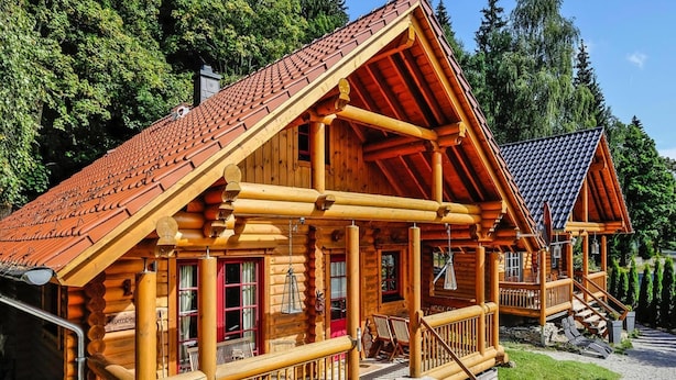 A log cabin with a porch, wooden steps, and a red roof. - Ferienhaus in Schierke mit Garten (Wernigerode)