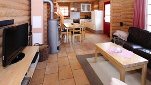A log cabin interior with a TV, fireplace, dining area, and living room. - Ferienhaus in Schierke mit Garten (Wernigerode)