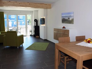 En moderne stue med sofa, spisebord og fjernsyn.