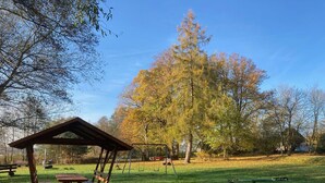 Ein Park mit einem hölzernen Pavillon, Picknicktischen, einer Schaukel und einem Spielplatz.